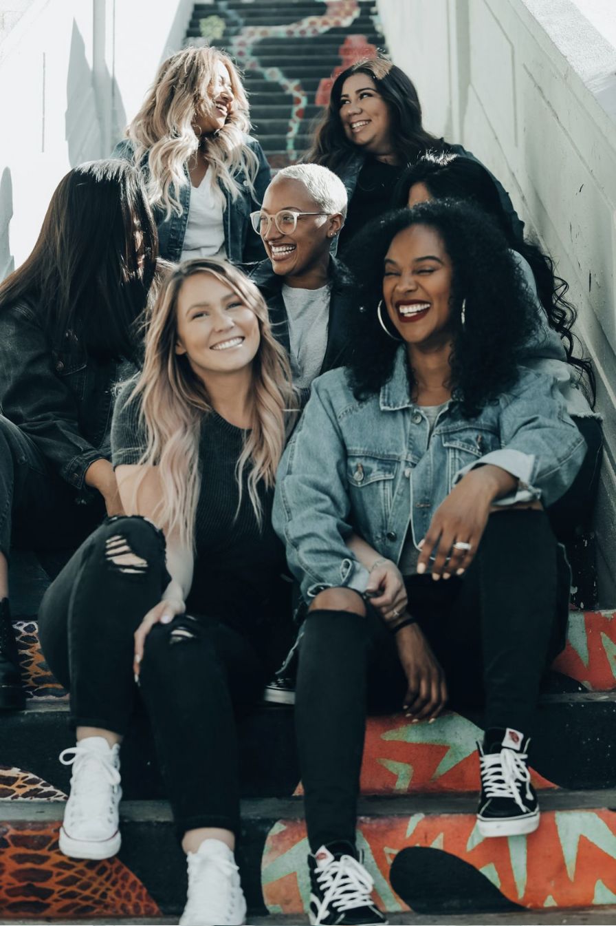 A group of women laughing together on a painted staircase